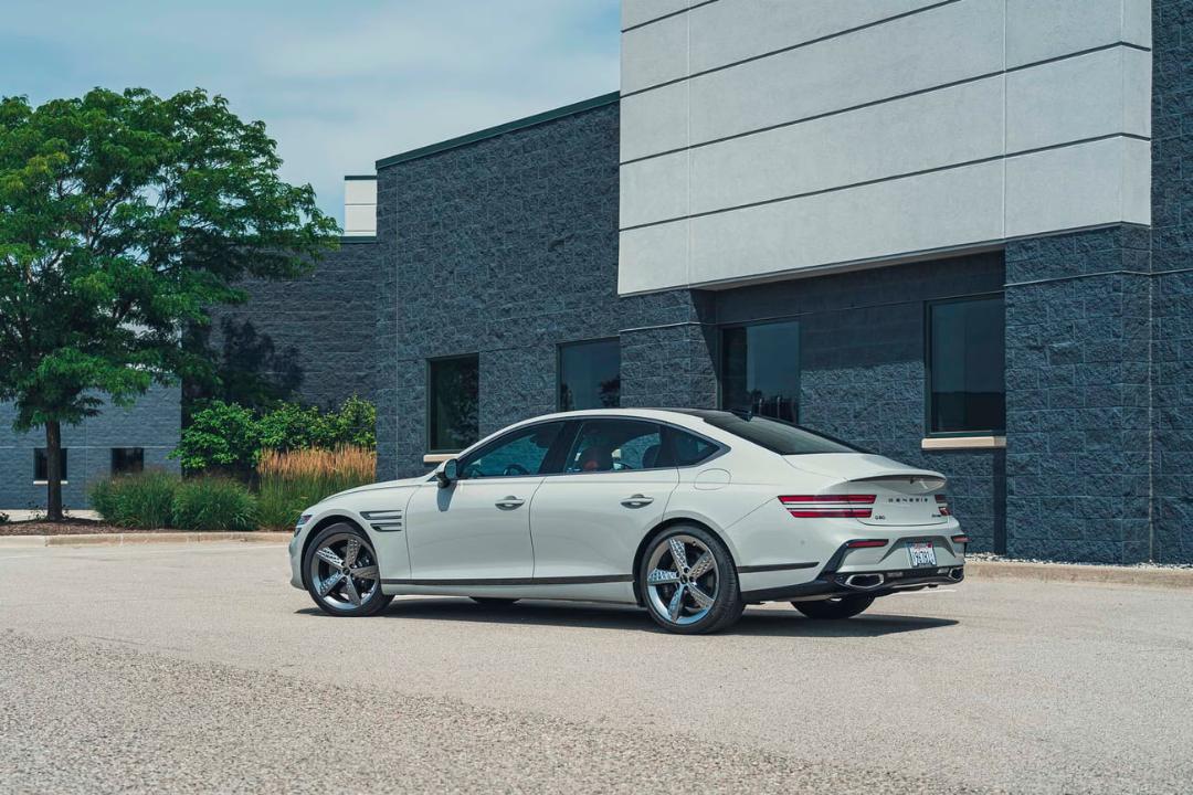 خودروی سفید رنگ جنسیس (Genesis) G80 در مقابل یک ساختمان مدرن