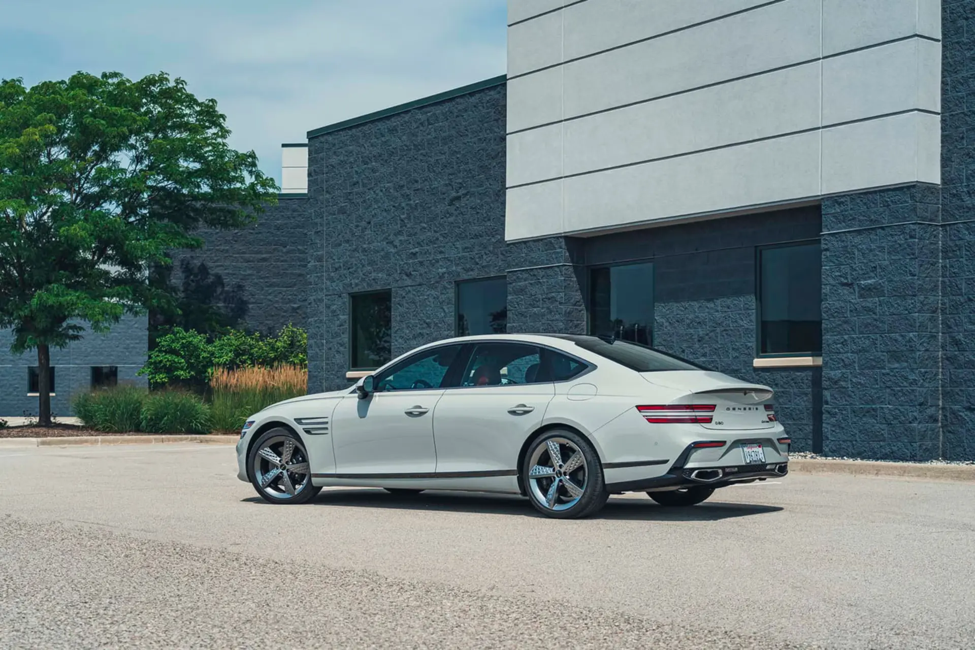 خودروی سفید رنگ جنسیس (Genesis) G80 در مقابل یک ساختمان مدرن