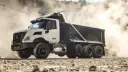 کامیون کمپرسی (Dump Truck) سفید و مشکی در حال حرکت در محیط معدن
