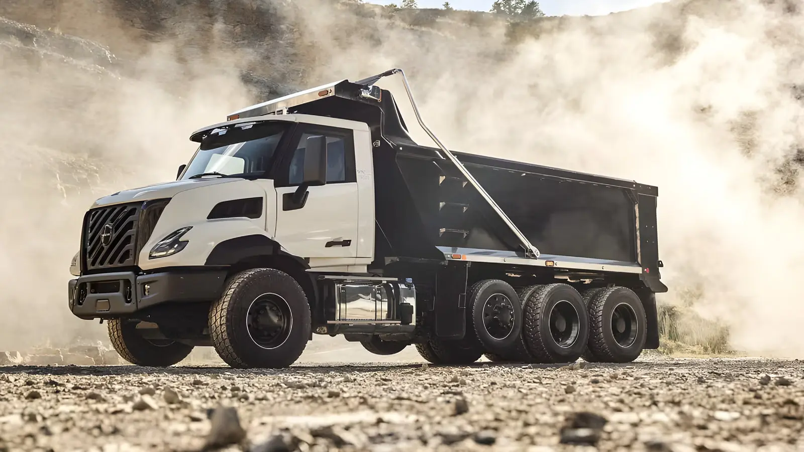 کامیون کمپرسی (Dump Truck) سفید و مشکی در حال حرکت در محیط معدن