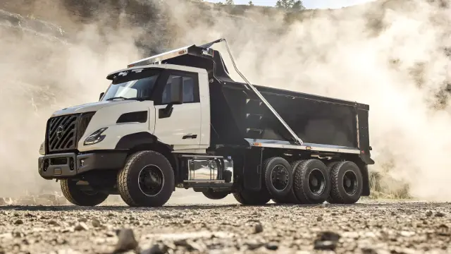 کامیون کمپرسی (Dump Truck) سفید و مشکی در حال حرکت در محیط معدن