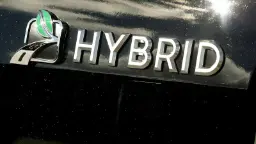 نشان فلزی کلمه HYBRID روی بدنه سیاه خودروی هیبریدی