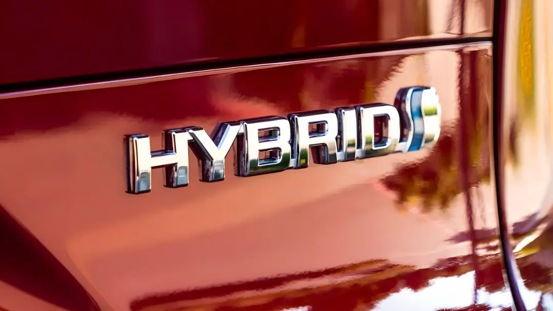 نشان فلزی کلمه HYBRID روی بدنه قرمز رنگ یک خودرو
