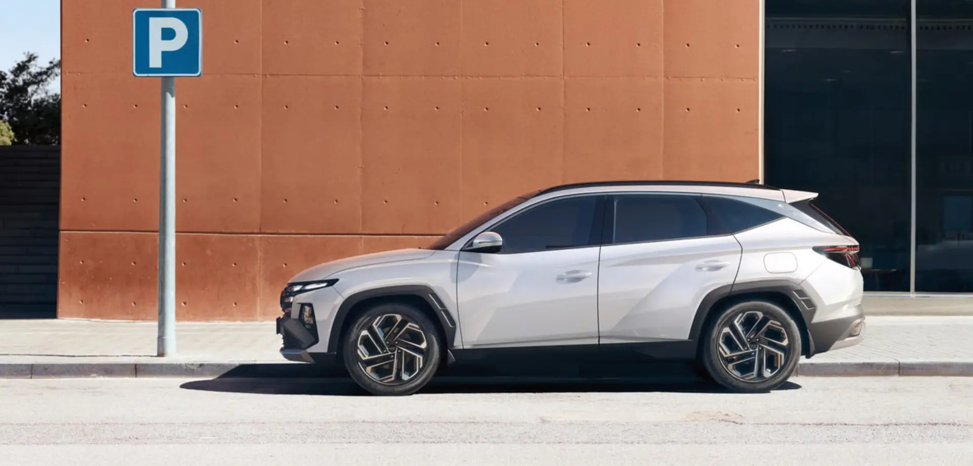 خودرو هیوندای (Hyundai) سفید رنگ در کنار تابلوی پارکینگ