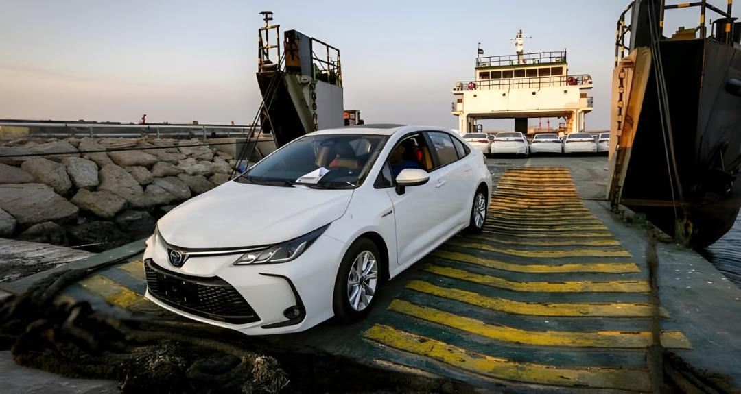 خودروی سفید وارداتی (Toyota Corolla) در حال خروج از رمپ کشتی حمل خودرو