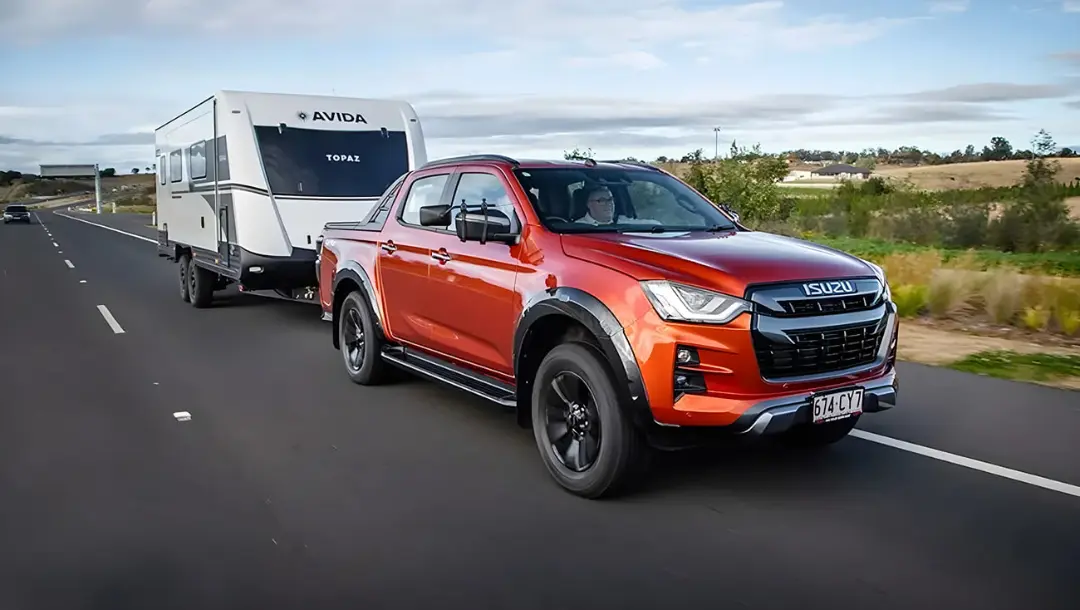 پیکاپ ایسوزو (Isuzu) در حال یدک‌کشی کاروان سفید در جاده