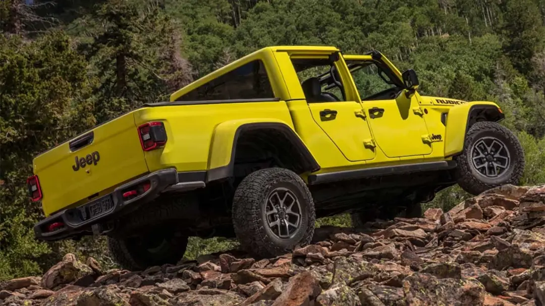 خودروی جیپ گلادیاتور (Jeep Gladiator) زرد رنگ در حال حرکت روی مسیر صخره‌ای