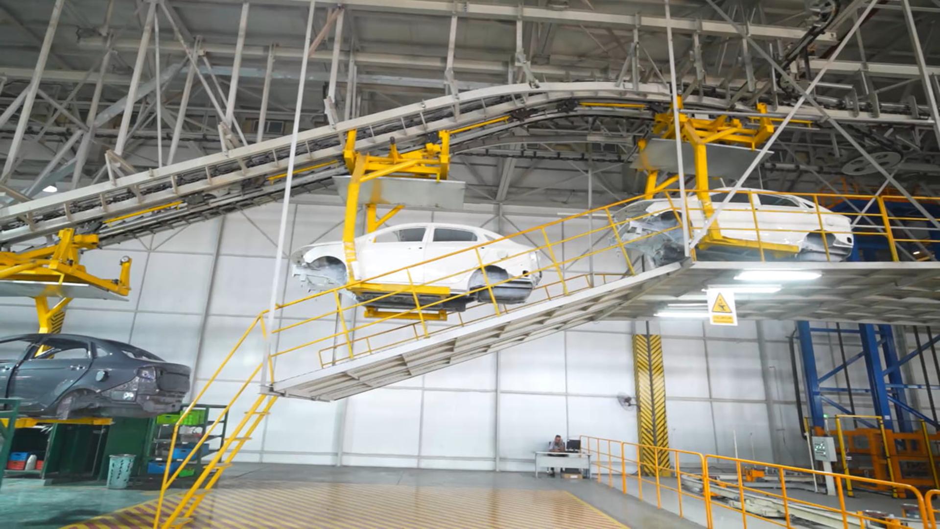 خودروهای سفید در خط تولید کرمان موتور (Kerman Motor) روی تسمه نقاله در حال حرکت هستند