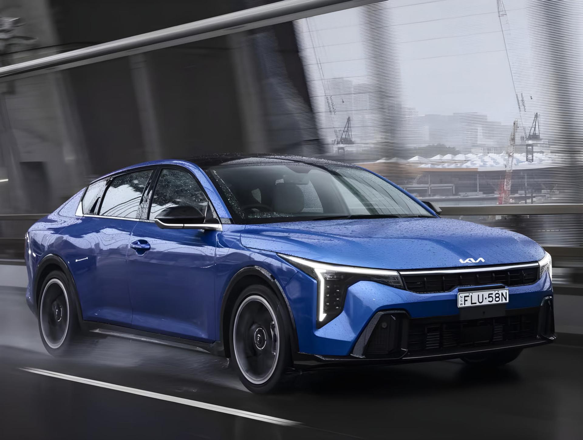 سدان آبی رنگ کیا (Kia K4) در حال حرکت در جاده بارانی