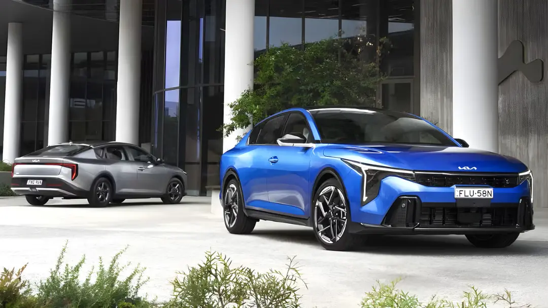 خودرو کیا K4 (Kia K4) سدان آبی و نقره‌ای در مقابل یک ساختمان مدرن
