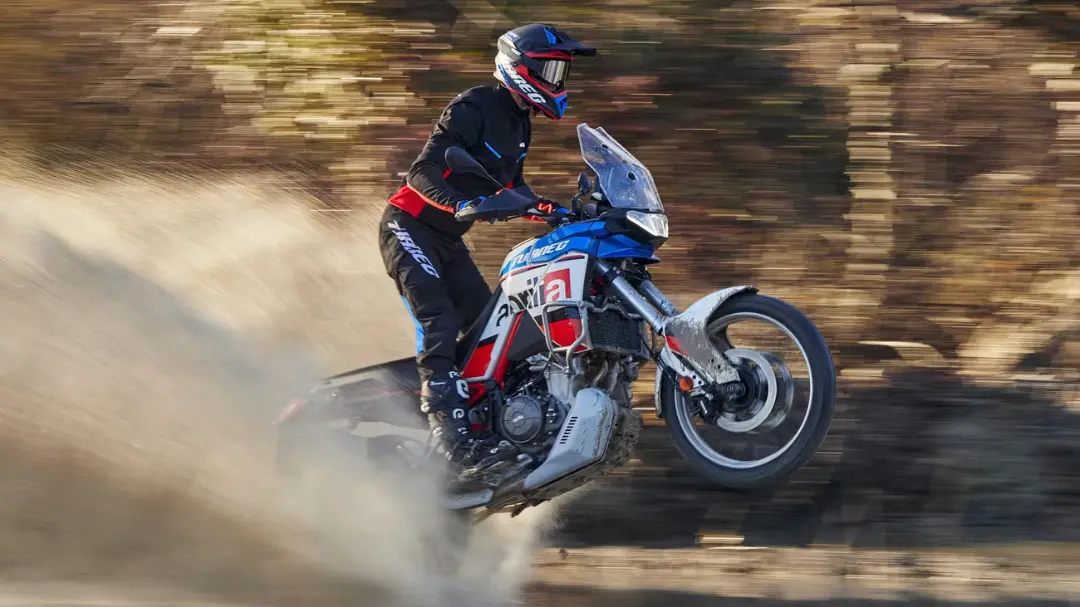 موتورسیکلت آپریلیا aprilia tuareg dakar podium در حال حرکت سریع در مسیر خاکی و برانگیختن گرد و غبار