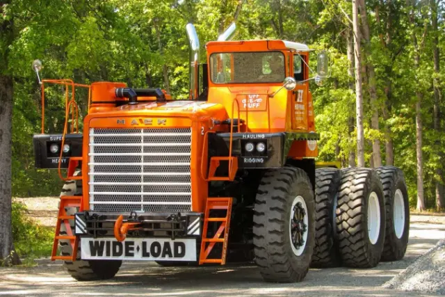 کامیون غول‌پیکر ماک (Mack M100SX) با رنگ نارنجی در محیط جنگلی