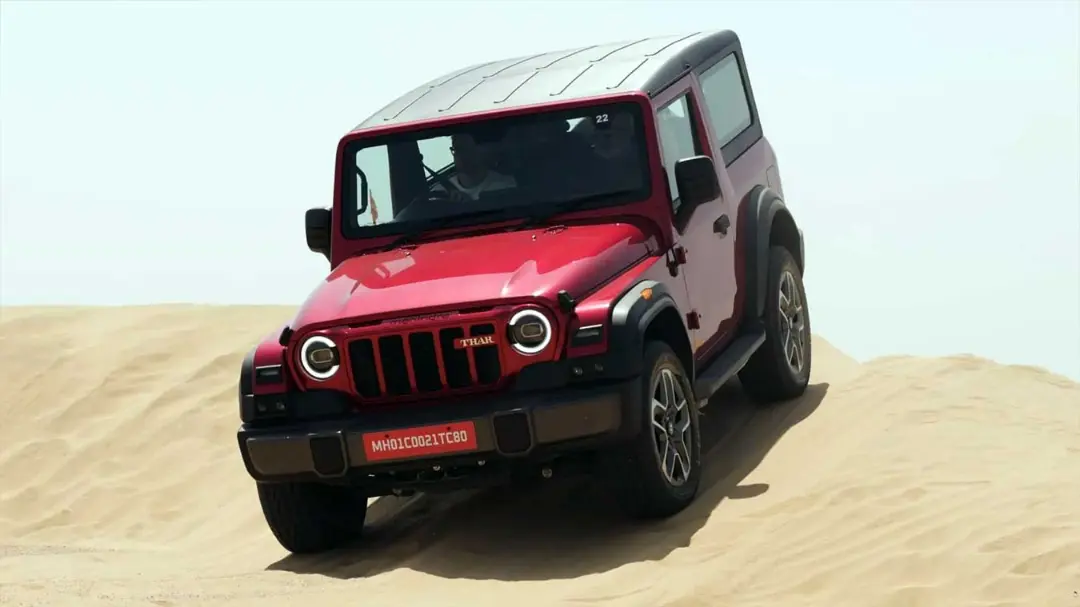خودرو ماهیندرا تار (Mahindra Thar) OG قرمز در حال حرکت روی تپه‌های شنی