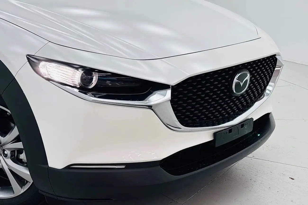 نمای نزدیک از جلوپنجره و چراغ‌های خودروی مزدا (Mazda) CX-30 سفید