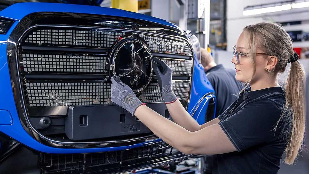 نصب نشان جلوی خودروی مرسدس بنز (Mercedes-Benz) توسط کارگر در خط تولید