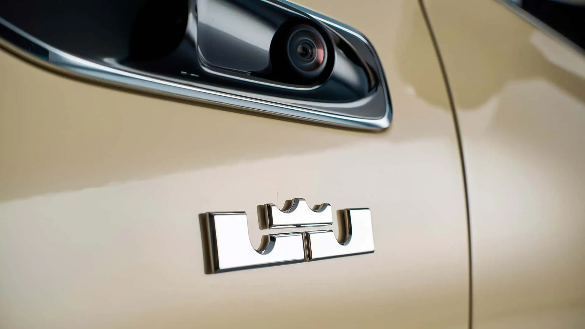 لوگوی کرومی برند میباخ (Maybach) روی بدنه خودروی کرم‌رنگ