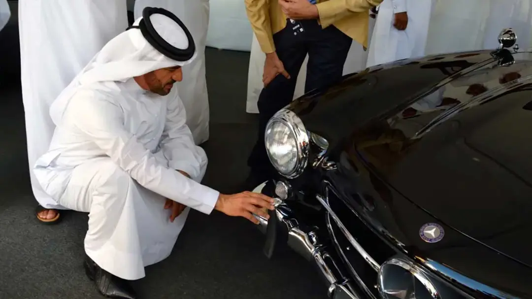 مردی با لباس سنتی عربی در حال بررسی جلوی خودروی کلاسیک مرسدس بنز (Mercedes-Benz)