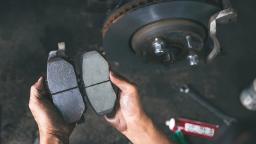 لنت ترمز نو در دست تعمیرکار در کنار دیسک ترمز خودرو