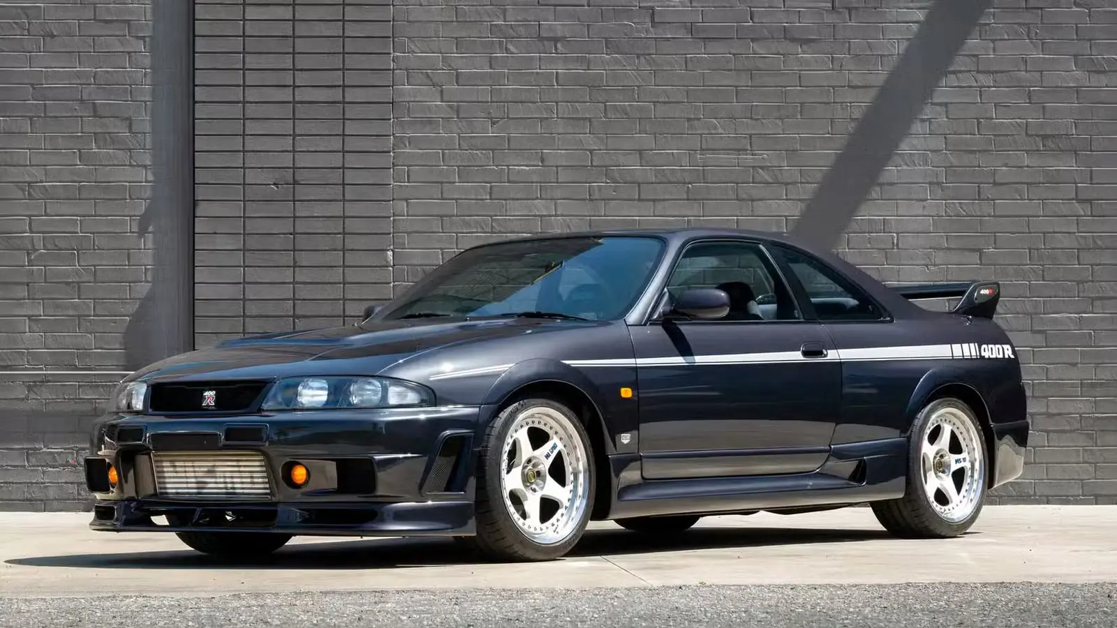 خودرو اسپرت نیسان 400R (Nissan 400R) با رنگ مشکی در مقابل دیوار خاکستری