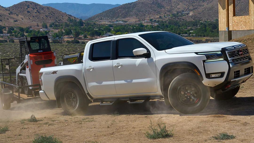 خودروی نیسان فرانتیر (Nissan Frontier) در حال یدک‌کشی یک دستگاه لودر کوچک در مسیر خاکی
