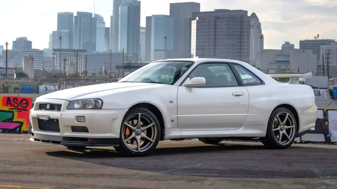 خودروی سفید نیسان اس‌کی‌و‌آر جی‌تی-آر (Nissan GT-R) مدل ۱۹۹۷ در مقابل خط افق شهری