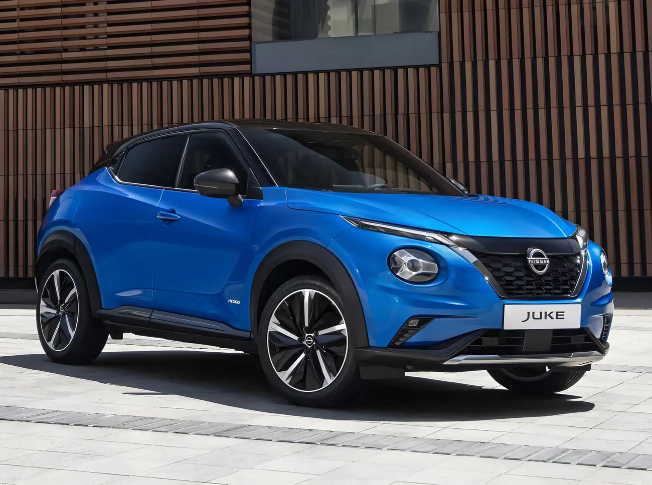 خودرو نیسان جوک (Nissan Juke) آبی رنگ در مقابل یک ساختمان مدرن
