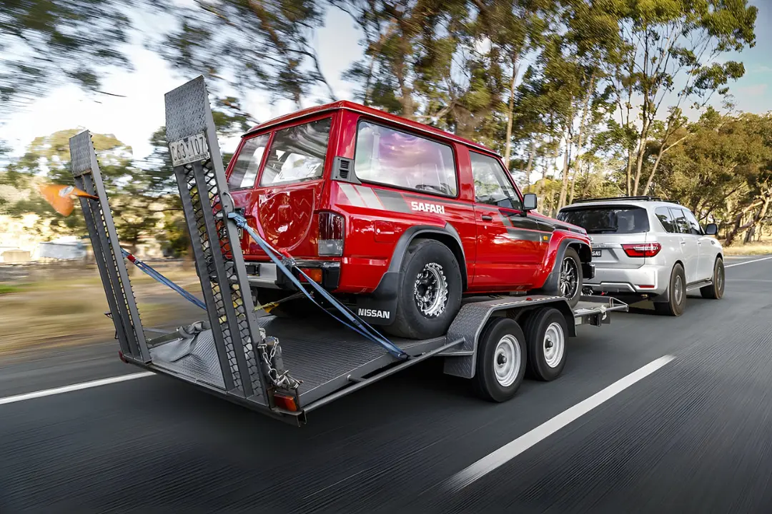 خودروی قرمز نیسان سافاری (Nissan Safari) روی تریلر حمل خودرو در حال حرکت