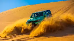 خودروی آفرود در حال حرکت سریع روی تپه‌های شنی و ایجاد گرد و غبار