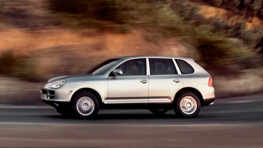 خودروی پورشه کاین (Porsche Cayenne) نقره‌ای در حال حرکت در جاده