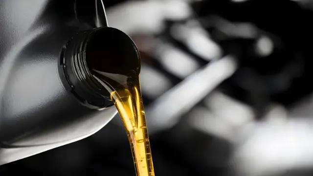 روغن موتور طلایی رنگ در حال ریختن از بطری سیاه