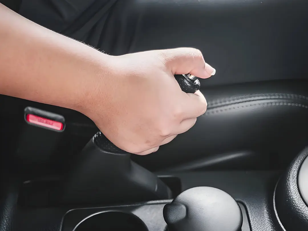 دست راننده در حال کشیدن اهرم ترمز دستی (Handbrake) خودرو