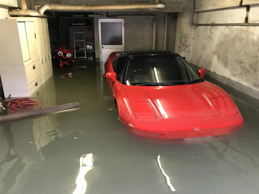 خودروی قرمز رنگ هوندای (Honda) غرق در آب در پارکینگ