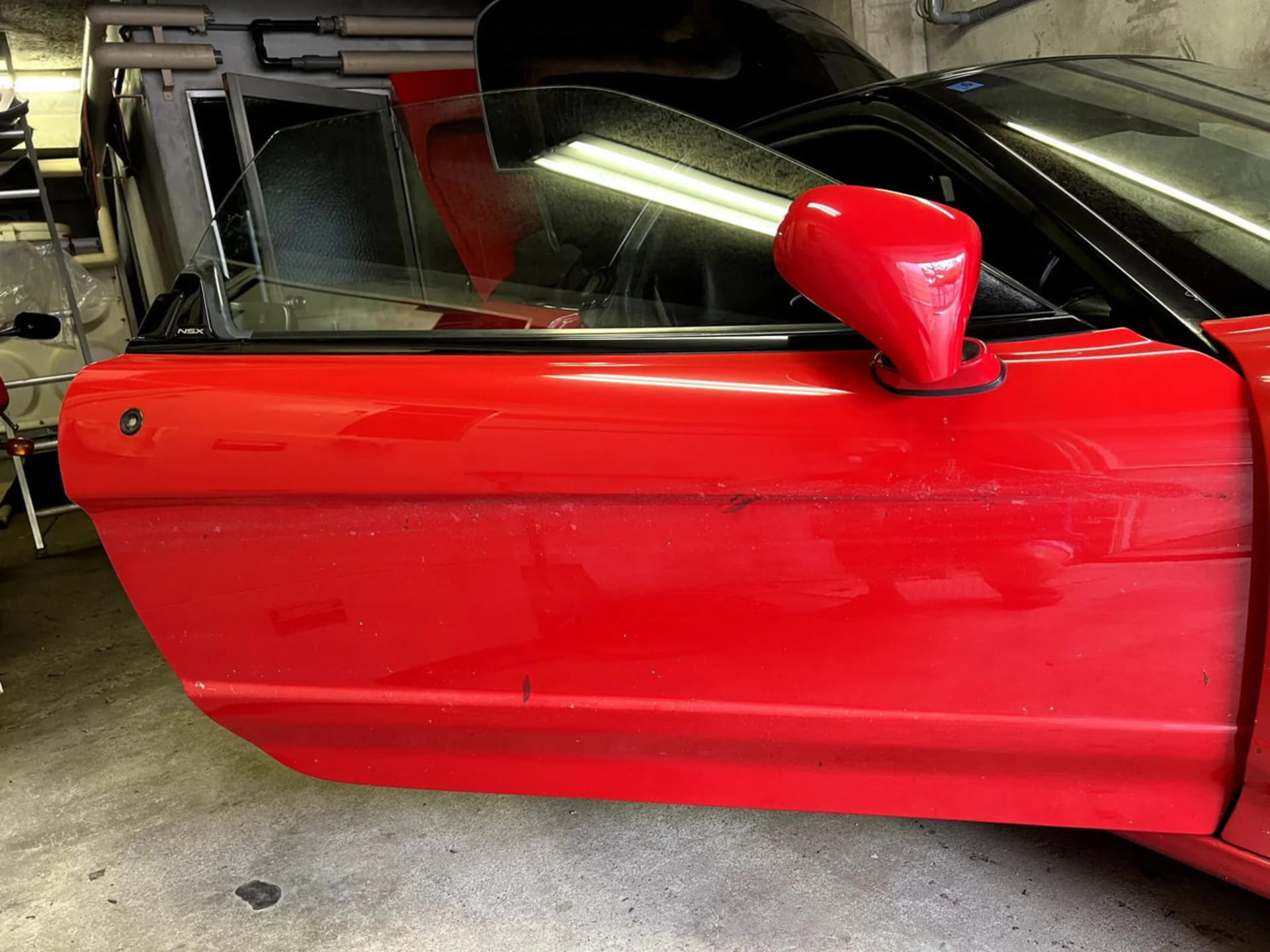 در خودروی قرمز رنگ هوندا (Honda NSX) که در پارکینگ قرار دارد