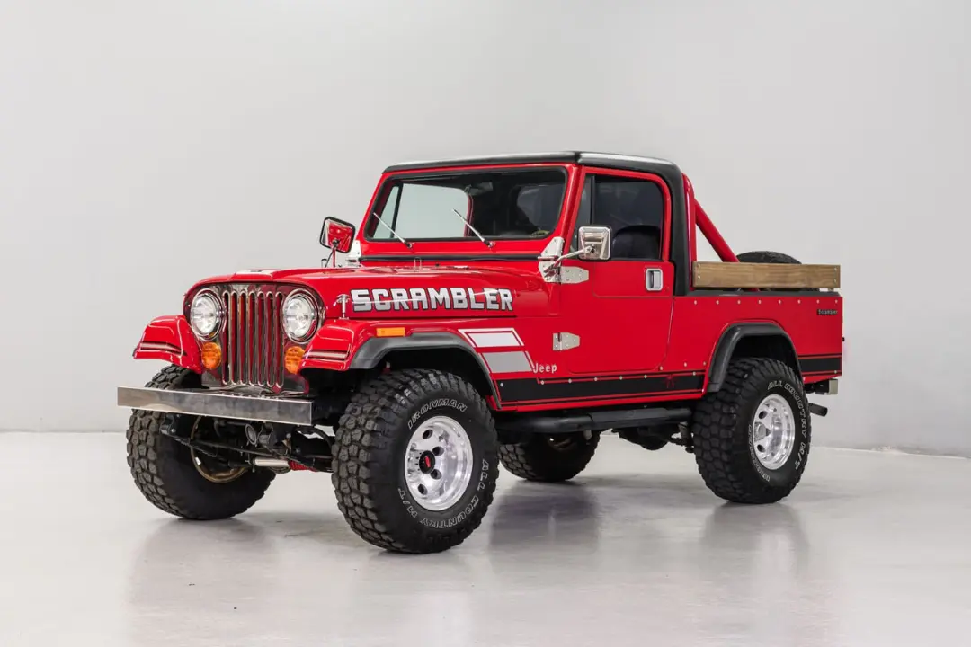 جیپ اسکرامبلر (Jeep Scrambler) قرمز رنگ با لاستیک‌های آفرود در استودیو