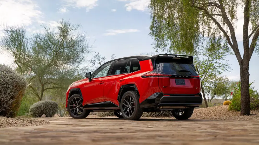 نمای نیم‌رخ از یک خودروی شاسی‌بلند RAV4 قرمز رنگ مدرن که در یک مسیر خاکی میان درختان پارک شده است.
