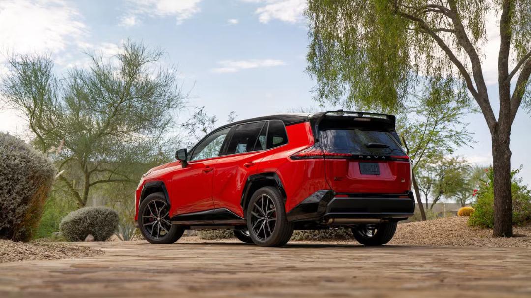 نمای نیم‌رخ از یک خودروی شاسی‌بلند RAV4 قرمز رنگ مدرن که در یک مسیر خاکی میان درختان پارک شده است.