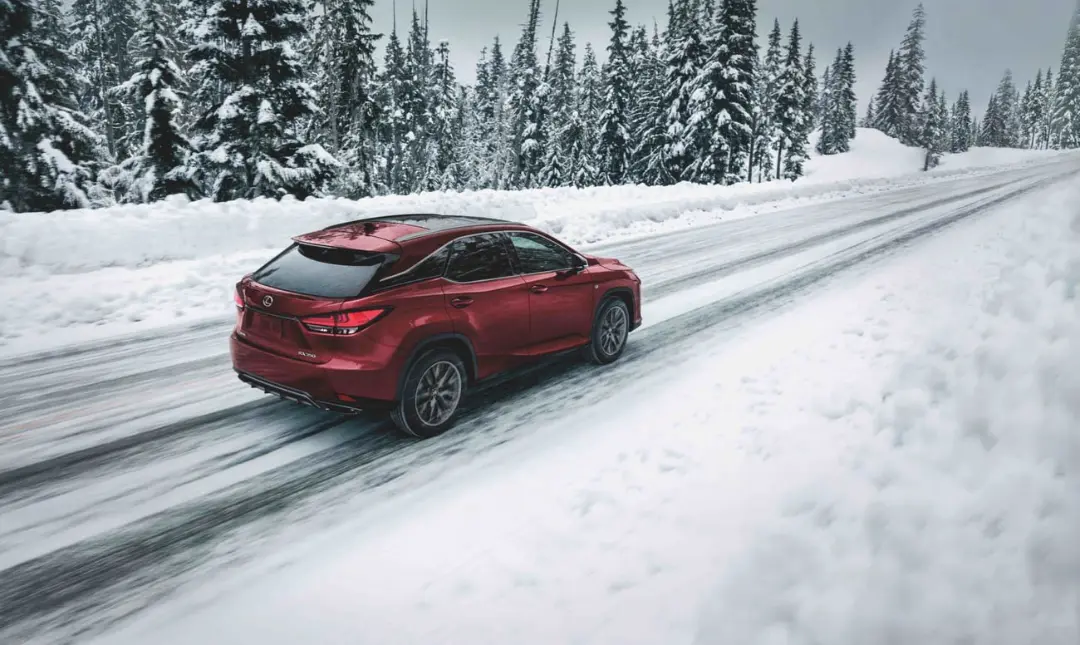 خودروی قرمز لکسوس (Lexus) در حال حرکت روی جاده‌ای پوشیده از برف