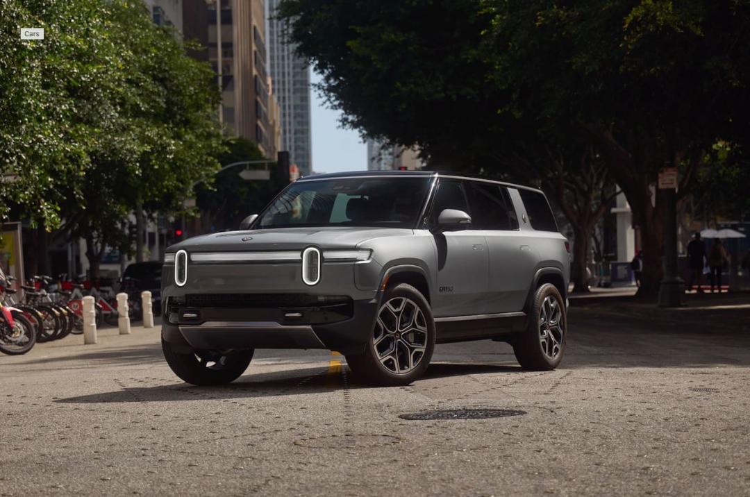 خودرو الکتریکی ریویان (Rivian R1S) در یک خیابان شهری با درختان سبز