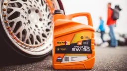 بطری روغن موتور ریماکس (Rymax) مدل Apollo C3 LL با ویسکوزیته 5W-30 در کنار چرخ خودرو