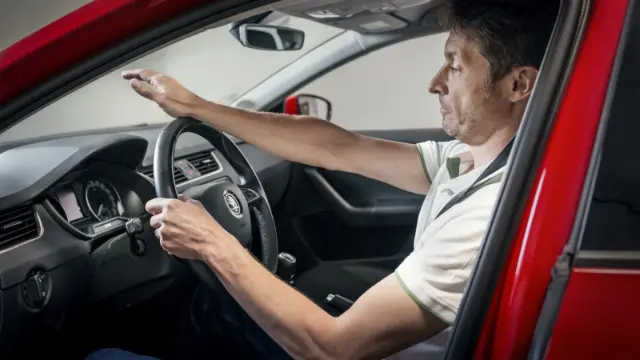 راننده خودرویی با برند اشک (Skoda) در حال تنظیم فاصله دست از فرمان