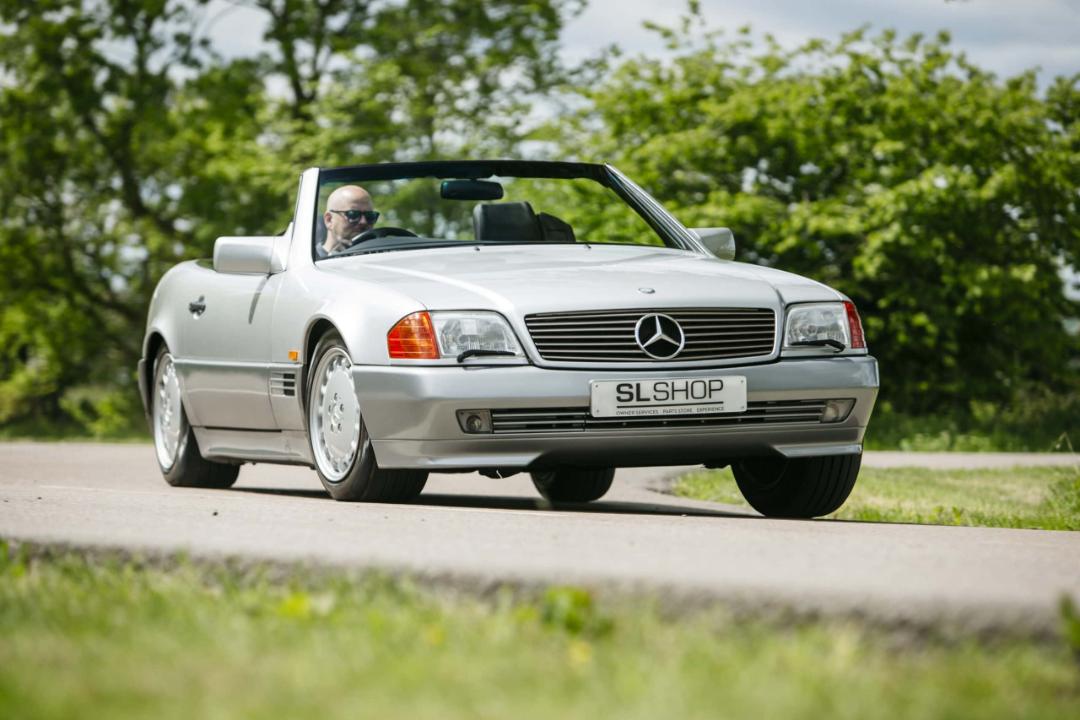 خودروی نقره‌ای مرسدس بنز (Mercedes-Benz) کلاس SL در حال حرکت در جاده