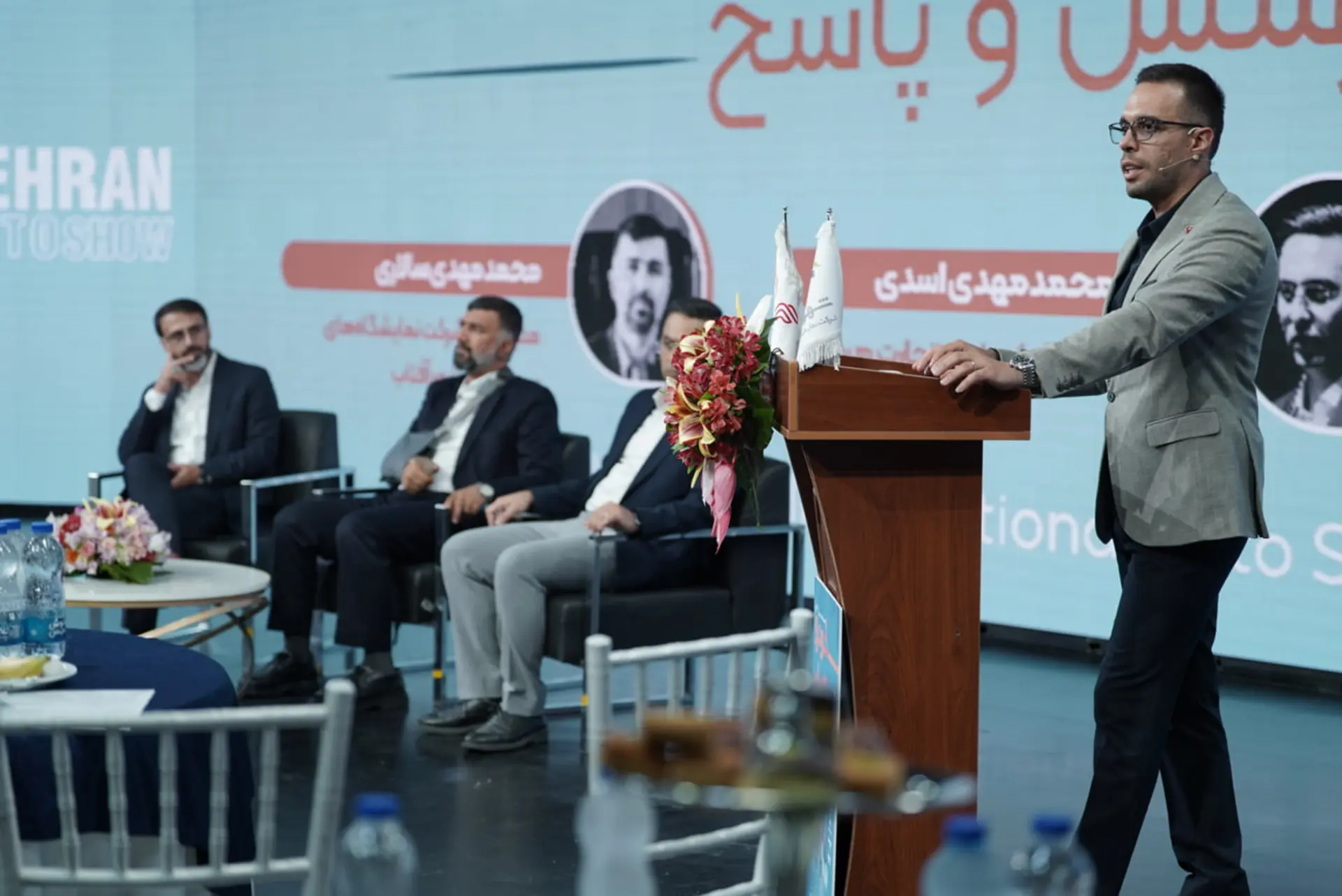 سخنران در نشست خبری هفتمین نمایشگاه خودرو تهران در مقابل میز پنل