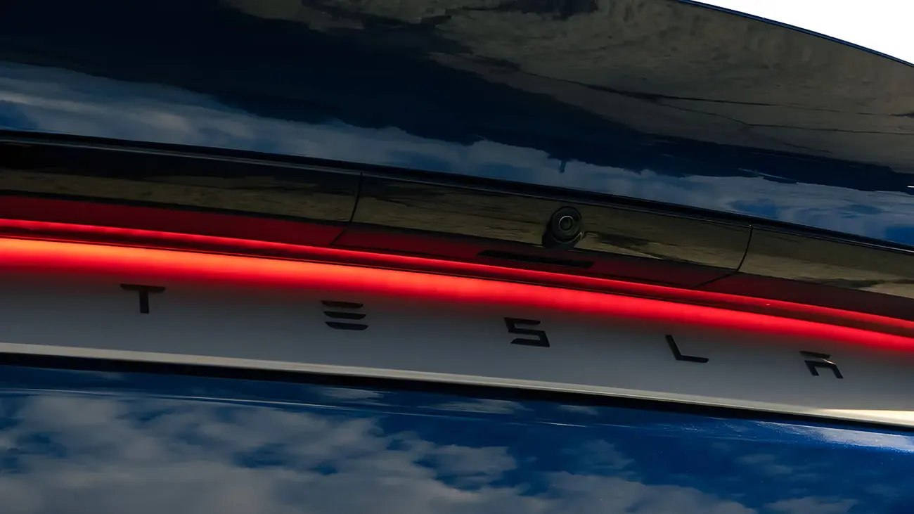 چراغ قرمز و لوگوی تسلا (Tesla) روی بدنه خودروی مدل Y