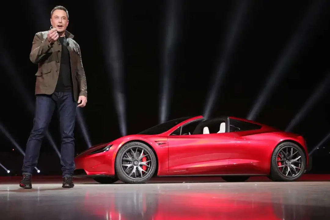 خودروی قرمز رنگ تسلا رودستر (Tesla Roadster) در کنار ایلان ماسک (Elon Musk)