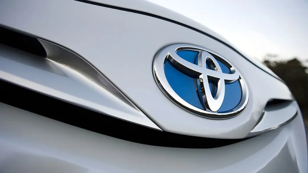 لوگوی برند تویوتا (Toyota) روی بدنه نقره‌ای خودرو
