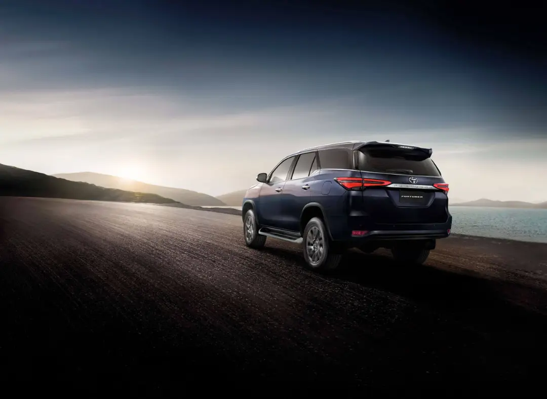 تویوتا فورچونر (Toyota Fortuner) آبی رنگ در جاده‌ای ساحلی هنگام غروب