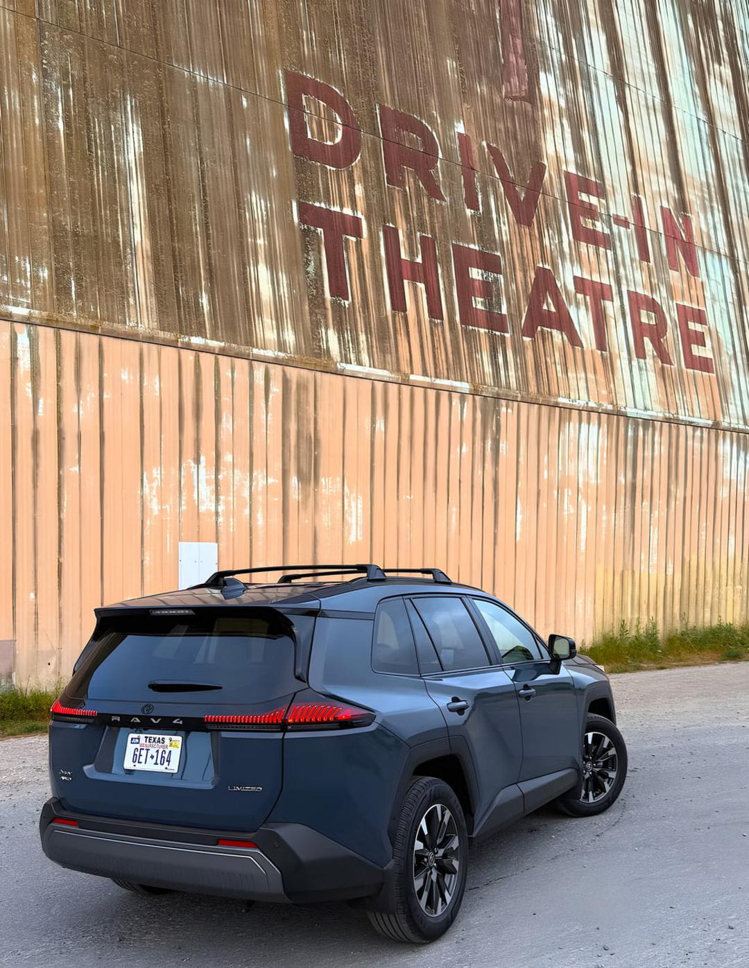 خودرو تویوتا راو4 (Toyota RAV4) هیبریدی پارک شده مقابل دیوار سینمای روباز