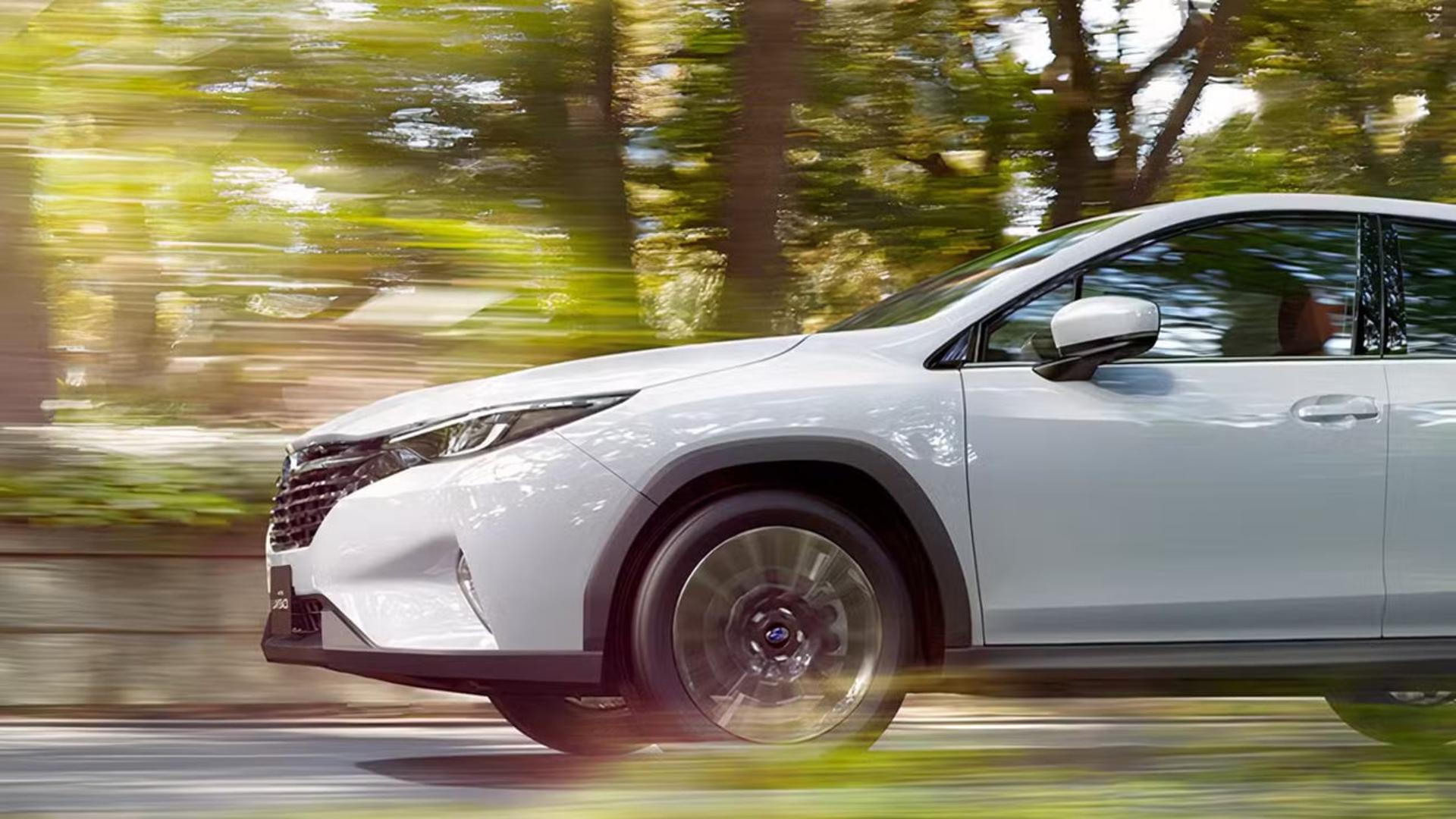 خودرو تویوتا (Toyota) RAV4 سفید در حال حرکت در جاده‌ای پوشیده از درختان