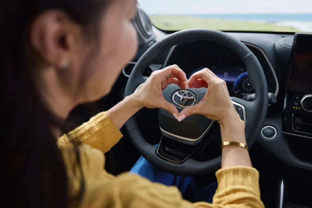 لوگوی تویوتا (Toyota) روی فرمان خودرو در دستان یک زن