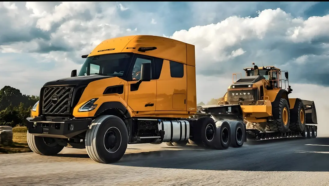 کامیون ولوو (Volvo) مدل VNX زرد رنگ در حال حمل لودر در جاده